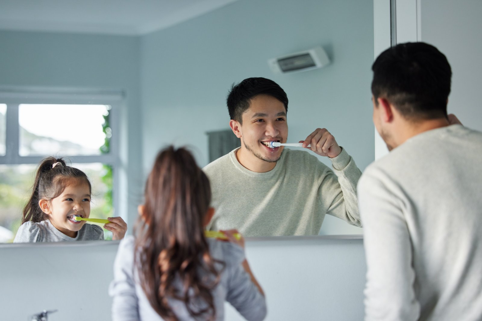 Parent helping child brush teeth as part of daily oral care routine